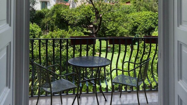 A balcony with a view of a cityscape, featuring a building with a red roof and a tree in the foreground. - THE BELLINI HOUSE (Naples)