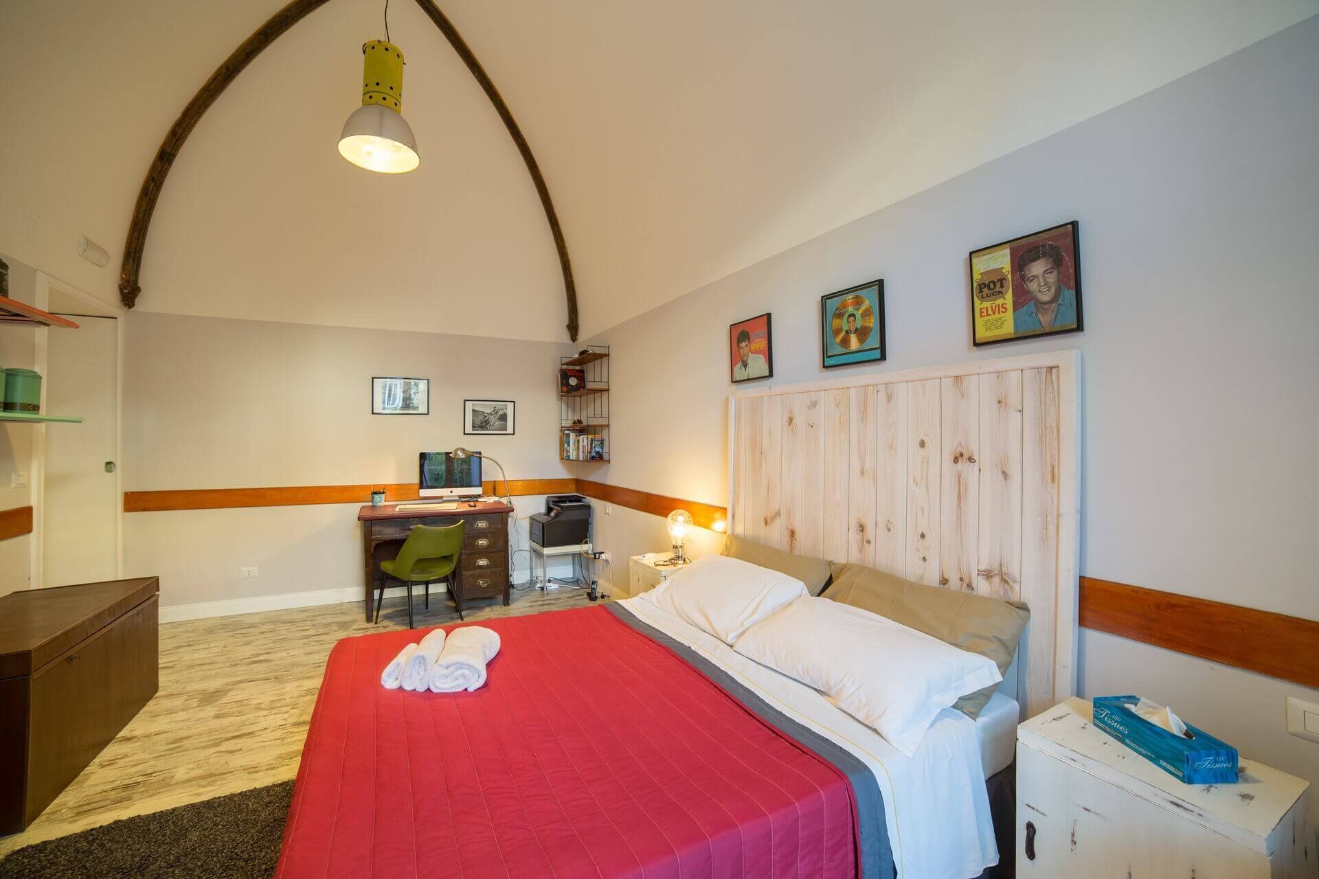 A bedroom with a bed, desk, chair, and a wooden headboard.