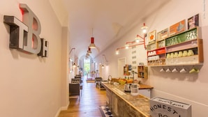 A hallway with a wooden floor, a bar area with a 'HONESTY BOX' sign, and various items on shelves. - THE BELLINI HOUSE (Naples)