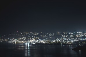A nighttime cityscape with a waterfront. - Villa Narciso (Mykonos)