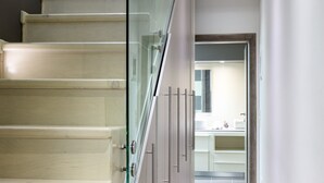 Una moderna scala con ringhiere in vetro che conduce a una zona cucina.