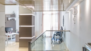 Un interno moderno con ringhiera in vetro, una scala e vista su un soggiorno.