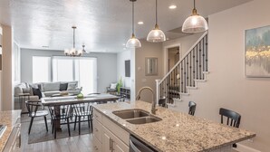 A modern kitchen with granite countertops, stainless steel appliances, and pendant lighting.