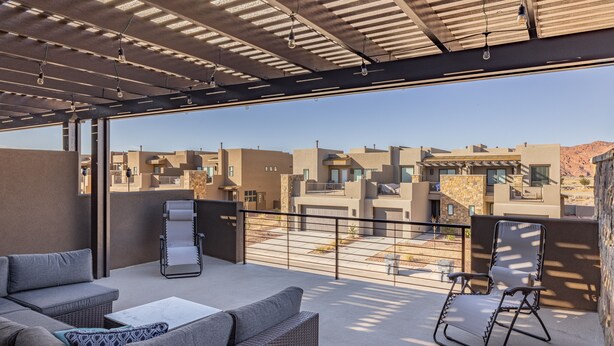 A rooftop terrace with outdoor furniture, a pergola, and a view of surrounding buildings.