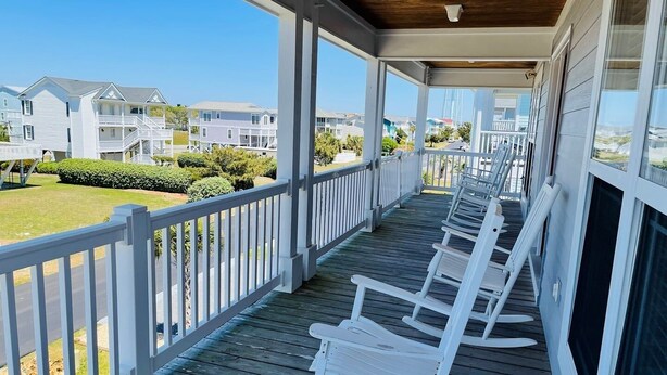 A covered porch with white rocking chairs, a wooden deck, and a view of neighboring houses. - Holden' A Full House 4 Bedroom Home by RedAwning (Supply)