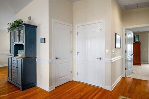 Un couloir doté d’un plancher en bois, de portes blanches et d’un meuble bleu foncé avec des tiroirs.