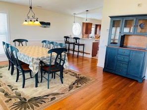 A dining area with a table, chairs, a rug, a hanging light fixture, and a kitchen area with cabinets. - Holden' A Full House 4 Bedroom Home by RedAwning (Supply)