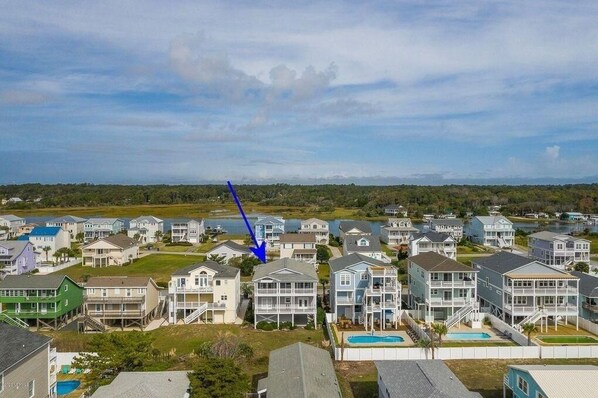 Il s’agit d’un quartier résidentiel situé sur la côte, avec de nombreuses maisons à deux étages, dont certaines sont dotées de balcons, et qui offre une vue dégagée sur l’eau en arrière-plan.
