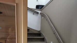 Un escalier en bois, doté d’une rampe et d’un luminaire fixé au mur.