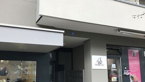 A building with a large glass storefront, a balcony, and a sign indicating the number 36. - RELOC Serviced Apartments Wallisellen 36 (Wallisellen)