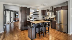 A modern kitchen with dark wood cabinets, stainless steel appliances, and a central island with bar stools. - 3/2 10 min Downtown Near Restaurants, Pet-Friendly (Austin)