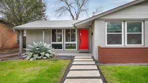A modern house with a red door, a covered porch, and a stone pathway leading to the entrance. - 3/2 10 min Downtown Near Restaurants, Pet-Friendly (Austin)