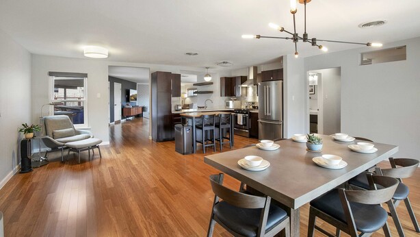 A modern kitchen with a central island, a dining area with a long table, and a seating arrangement. - 3/2 10 min Downtown Near Restaurants, Pet-Friendly (Austin)