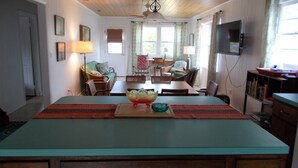 Una cocina con isla central, mesa de comedor, sillas y televisor montado en la pared.