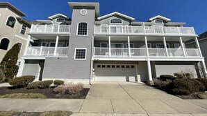 A multi-story residential building with a central tower, multiple balconies, and a garage.