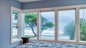 A bedroom with a large window overlooking a tree and a body of water.