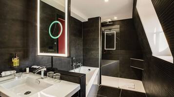 A modern bathroom with a large mirror, two sinks, a bathtub, and a glass shower enclosure.