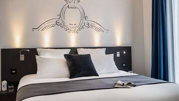 Una habitación de hotel moderna con una cama grande, un elemento decorativo en la pared y una mesita de noche con una lámpara.