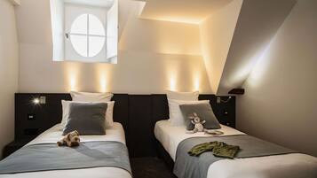 A hotel room with two beds, a skylight, and a small window.