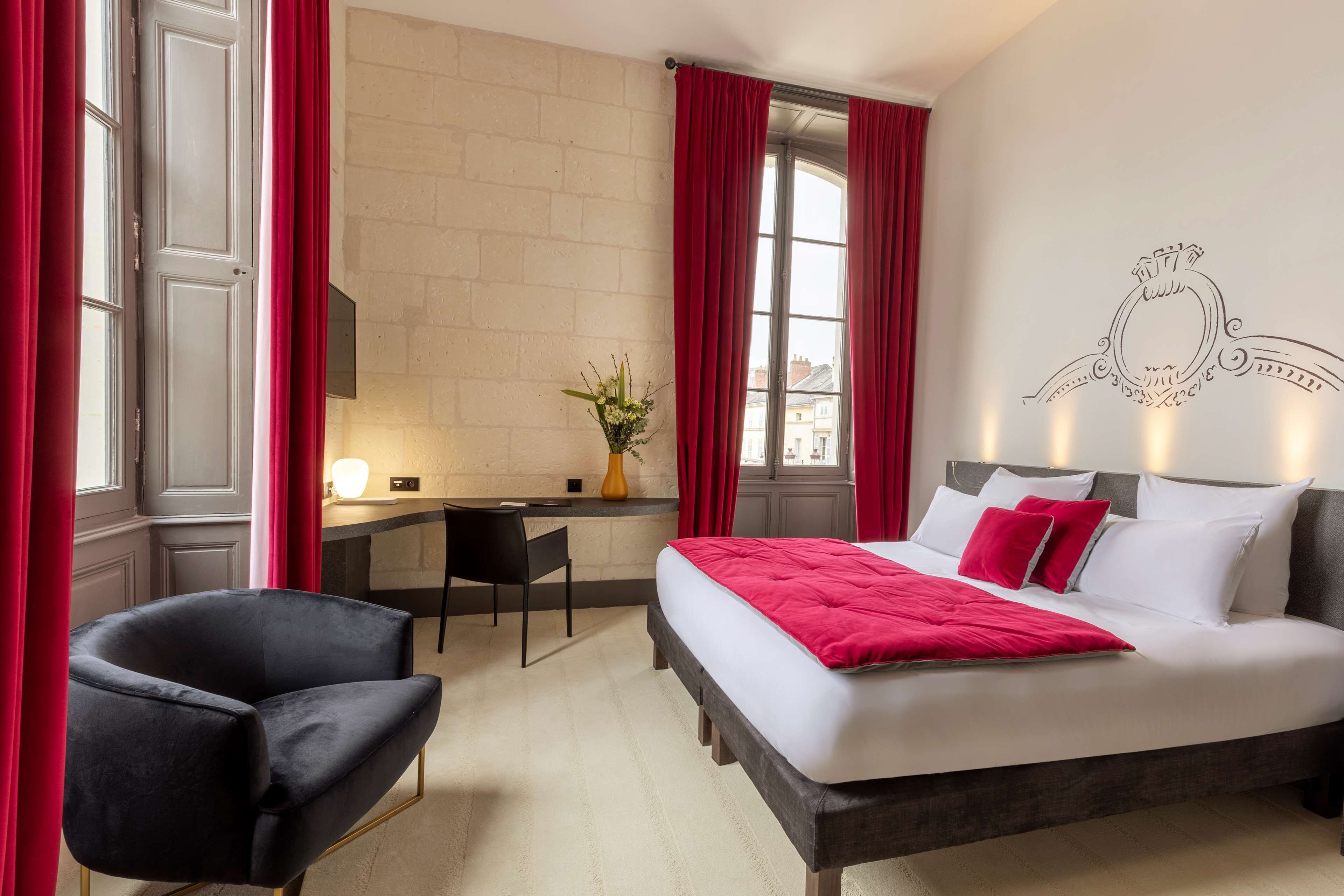 A hotel room with a bed, a desk, a chair, and a window with curtains.