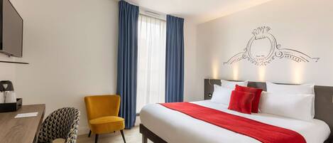 A hotel room with a large bed, a desk with a chair, a television, and a window with curtains.