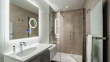 Une salle de bain moderne avec un grand miroir, un lavabo et une douche à parois de verre.