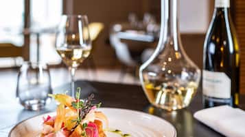Une table à manger avec une assiette de nourriture, une bouteille de vin et des verres.