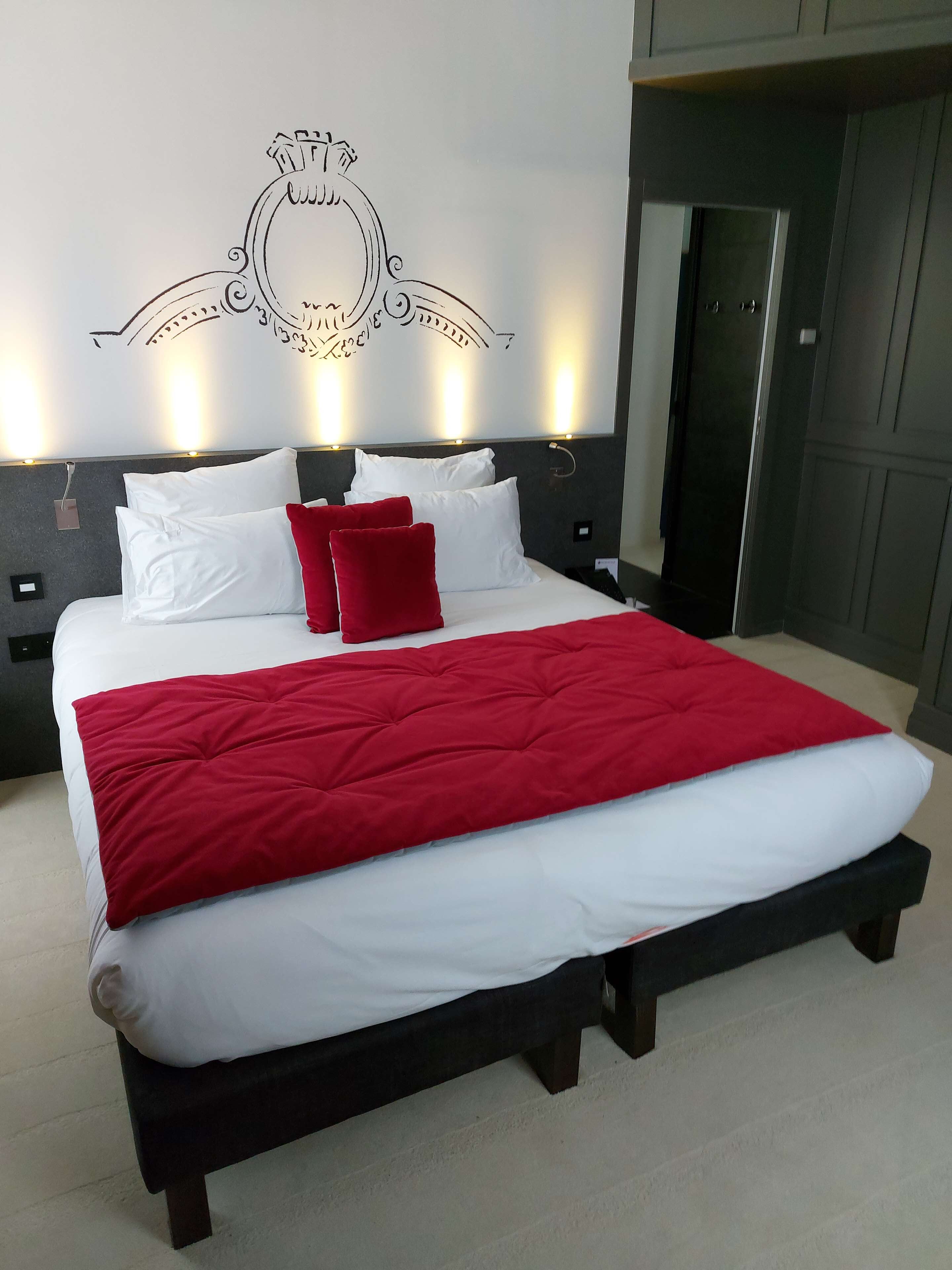Una camera da letto moderna con un letto grande, biancheria rossa e bianca e un motivo decorativo al muro.