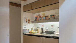 A kitchen with wooden beams, a countertop with various food items, and a coffee machine. - Atik Rooms (Ljubljana)