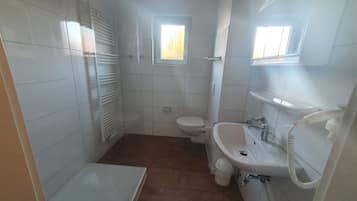 Un baño pequeño con azulejos, un inodoro, lavamanos y ducha.