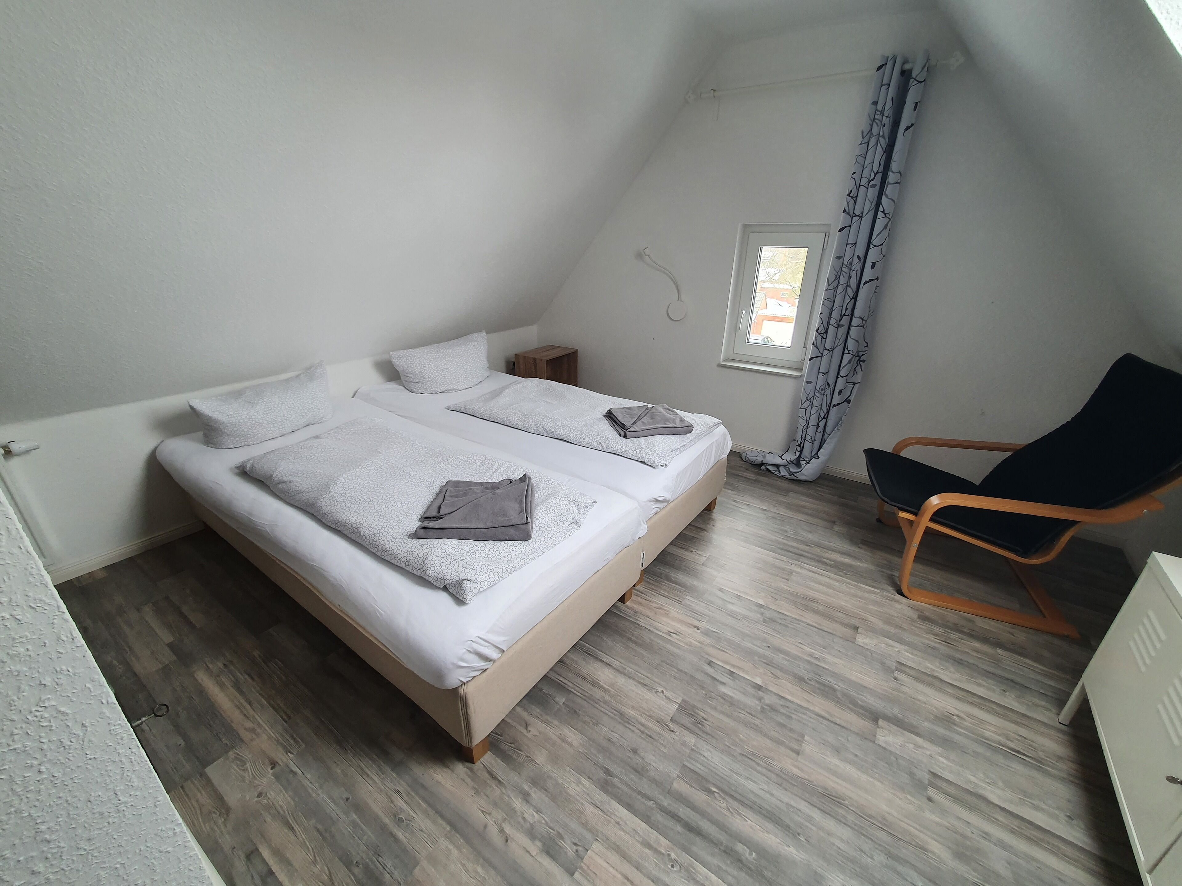 Un dormitorio con dos camas, una silla y una ventana.