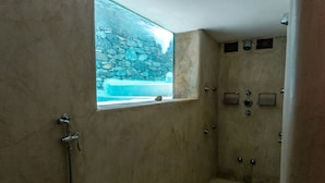Une douche à l’italienne avec un mur en pierre et une fenêtre donnant sur une piscine.