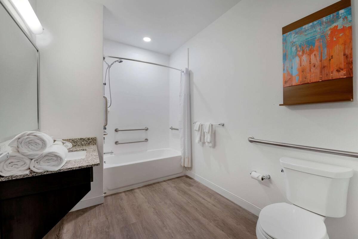 A modern bathroom with a bathtub, toilet, and a shower.