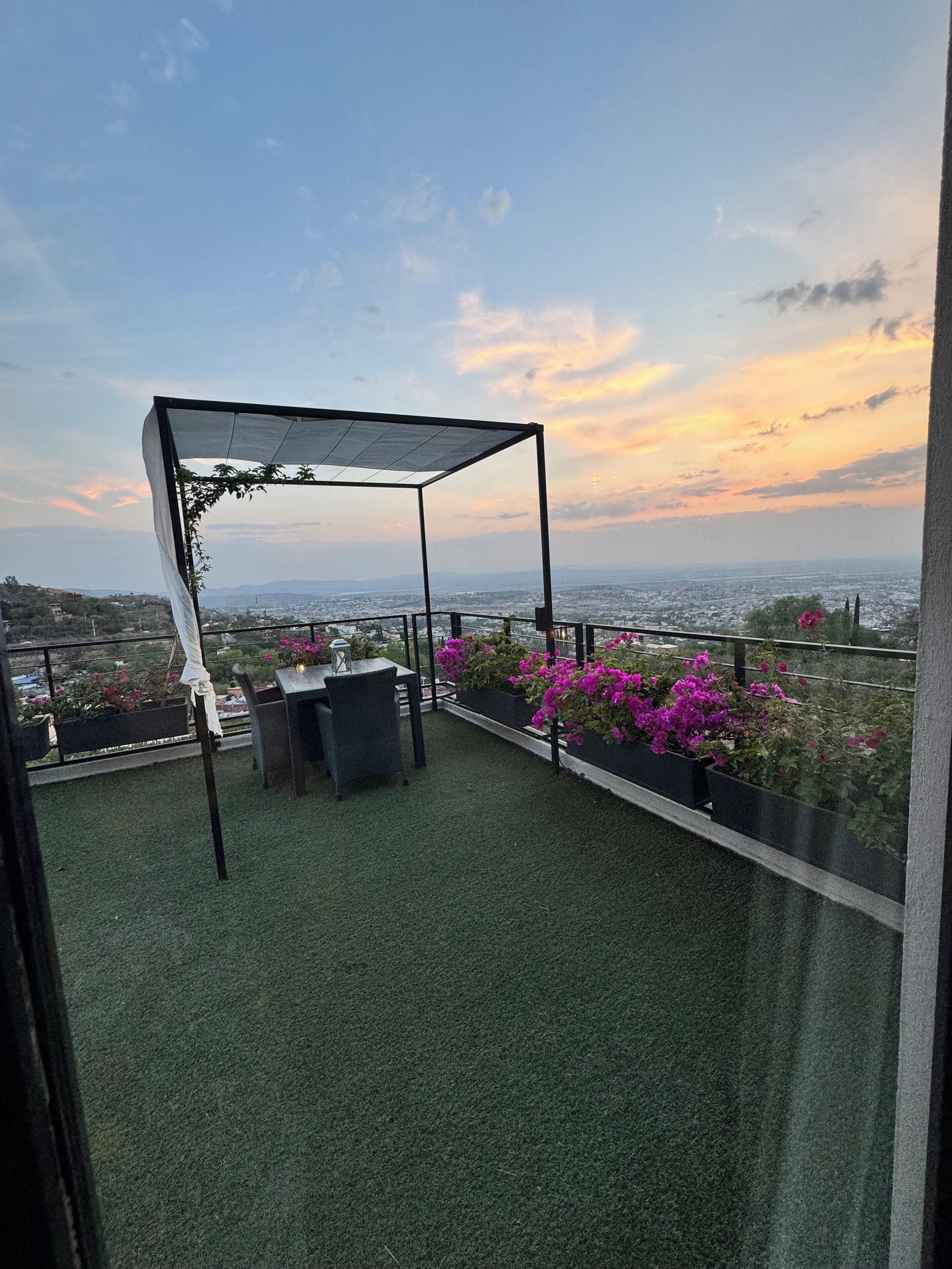 Eine Dachterrasse mit Pergola, Sitzgelegenheit und Topfpflanzen.