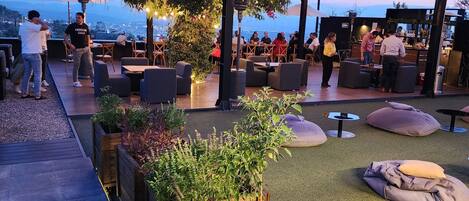 An outdoor seating area with wooden planters, tables, and chairs under a covered patio.