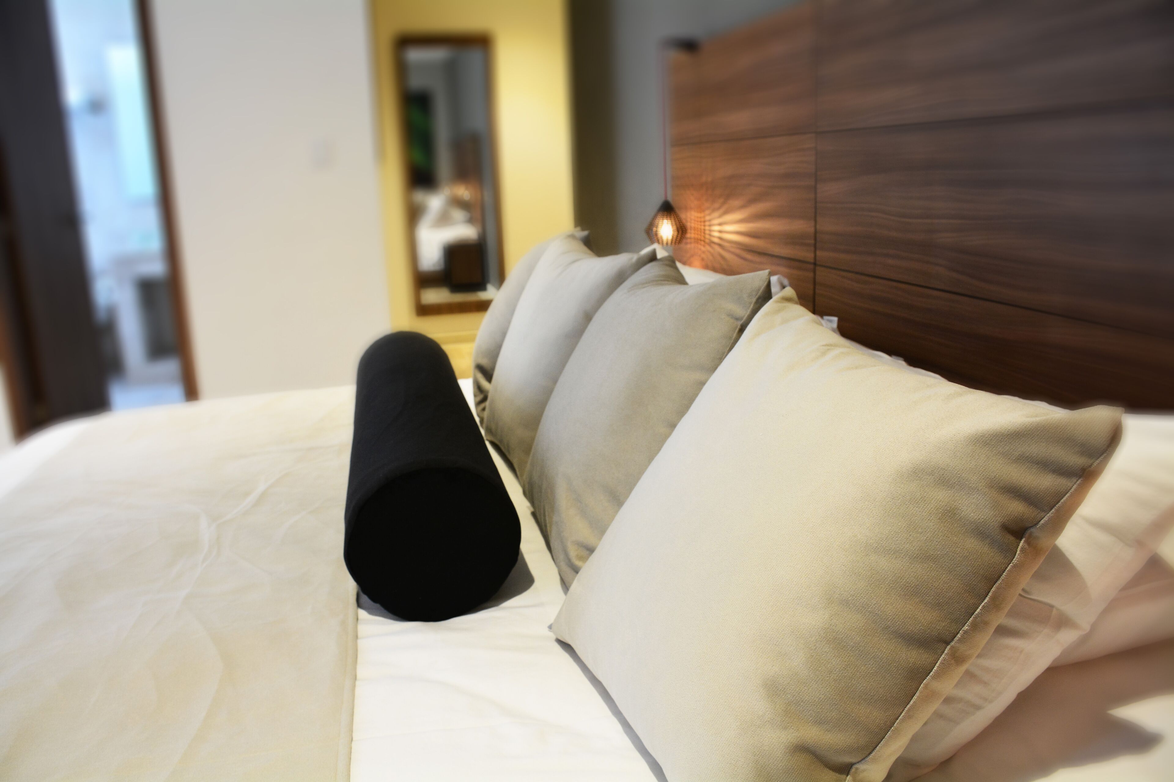 Una cama con muchos almohadones y un cabecero.