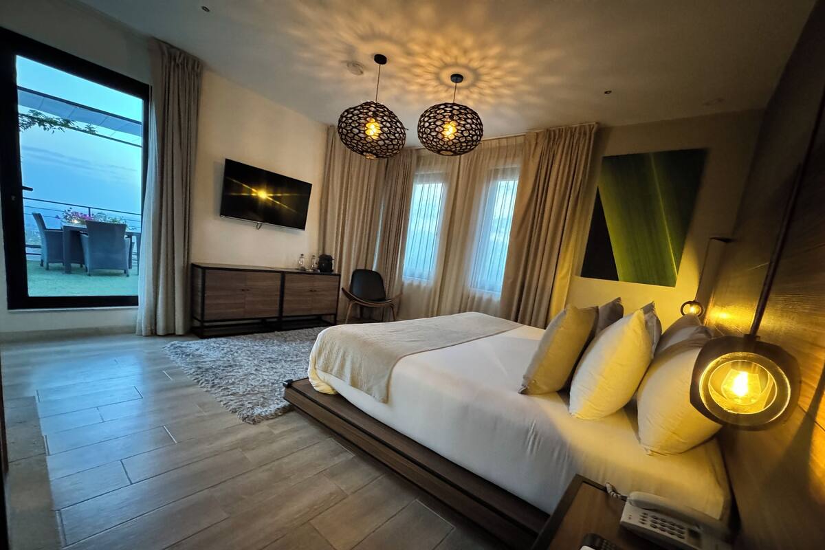 Une chambre moderne dotée d’un grand lit, d’un téléviseur à écran plat, d’un bureau avec un téléphone et offrant une vue sur l’extérieur.