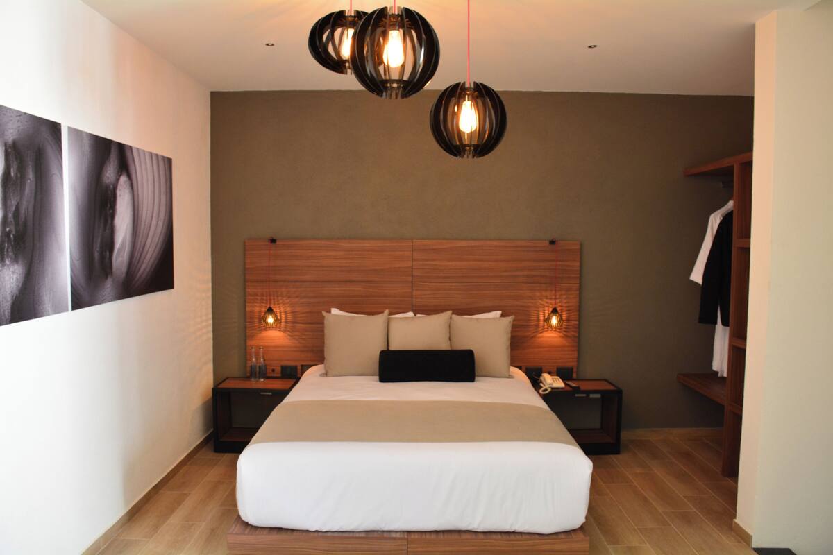 Une chambre moderne avec un grand lit, une tête de lit en bois, des lampes de chevet et une armoire.