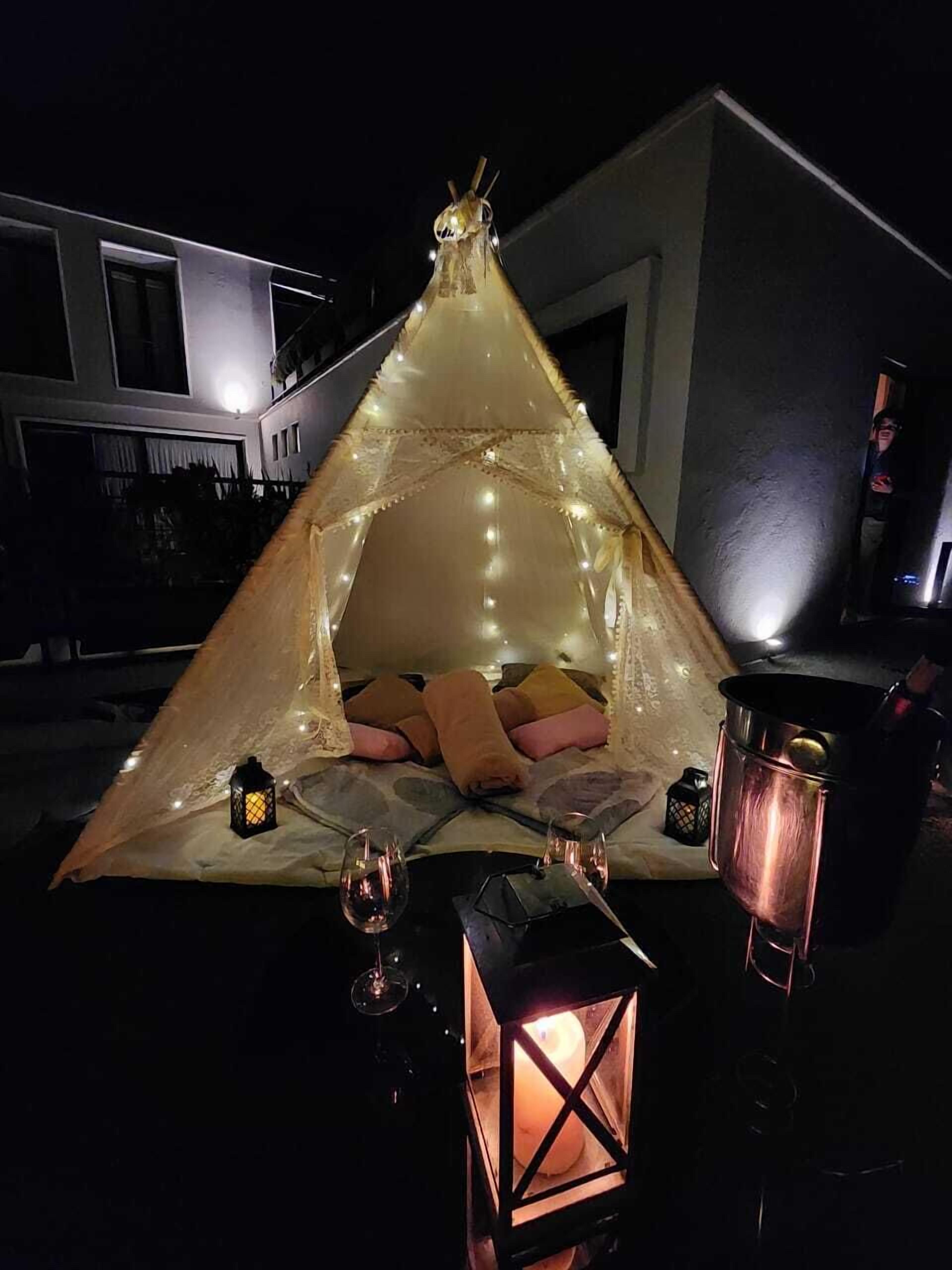 Una carpa con un área para dormir, dos faroles y una vela.