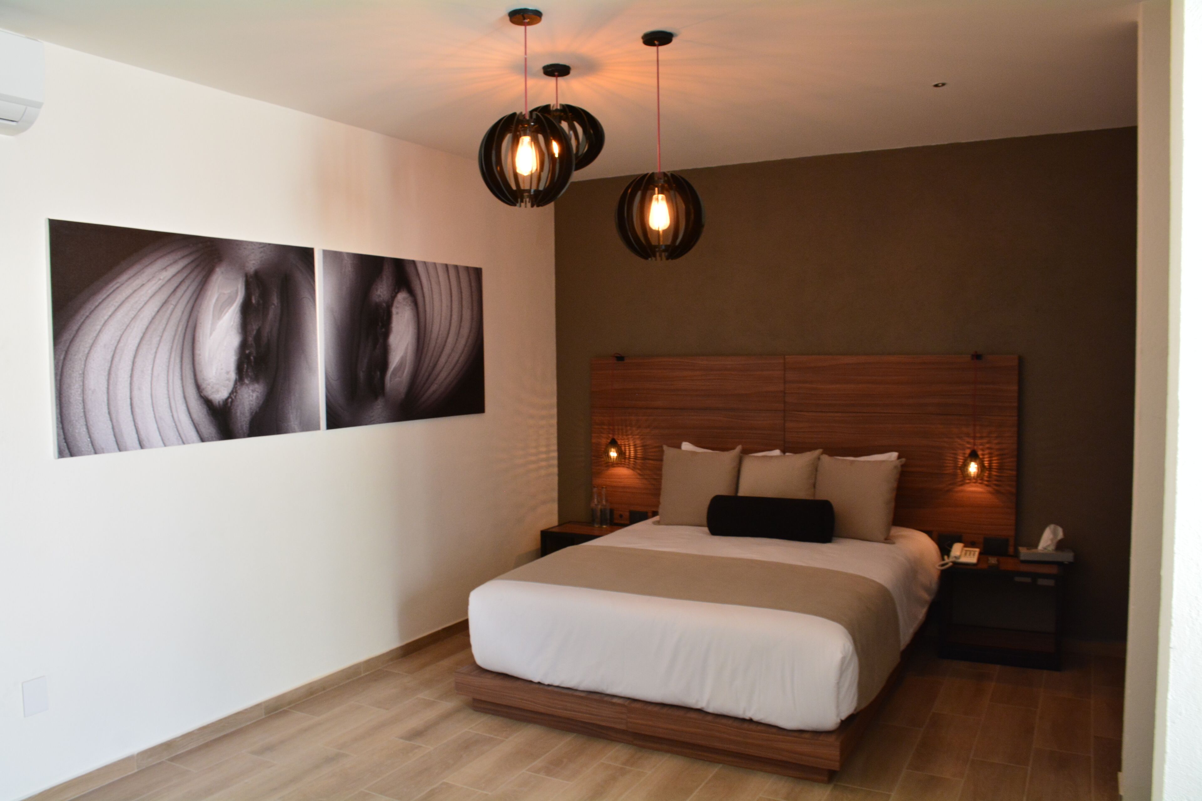 A modern bedroom with a large bed, two bedside tables, and a wall-mounted artwork.