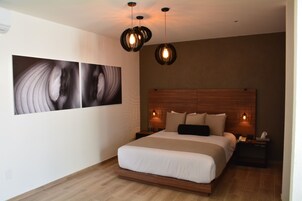 A modern bedroom with a large bed, two bedside tables, and a wall-mounted artwork.