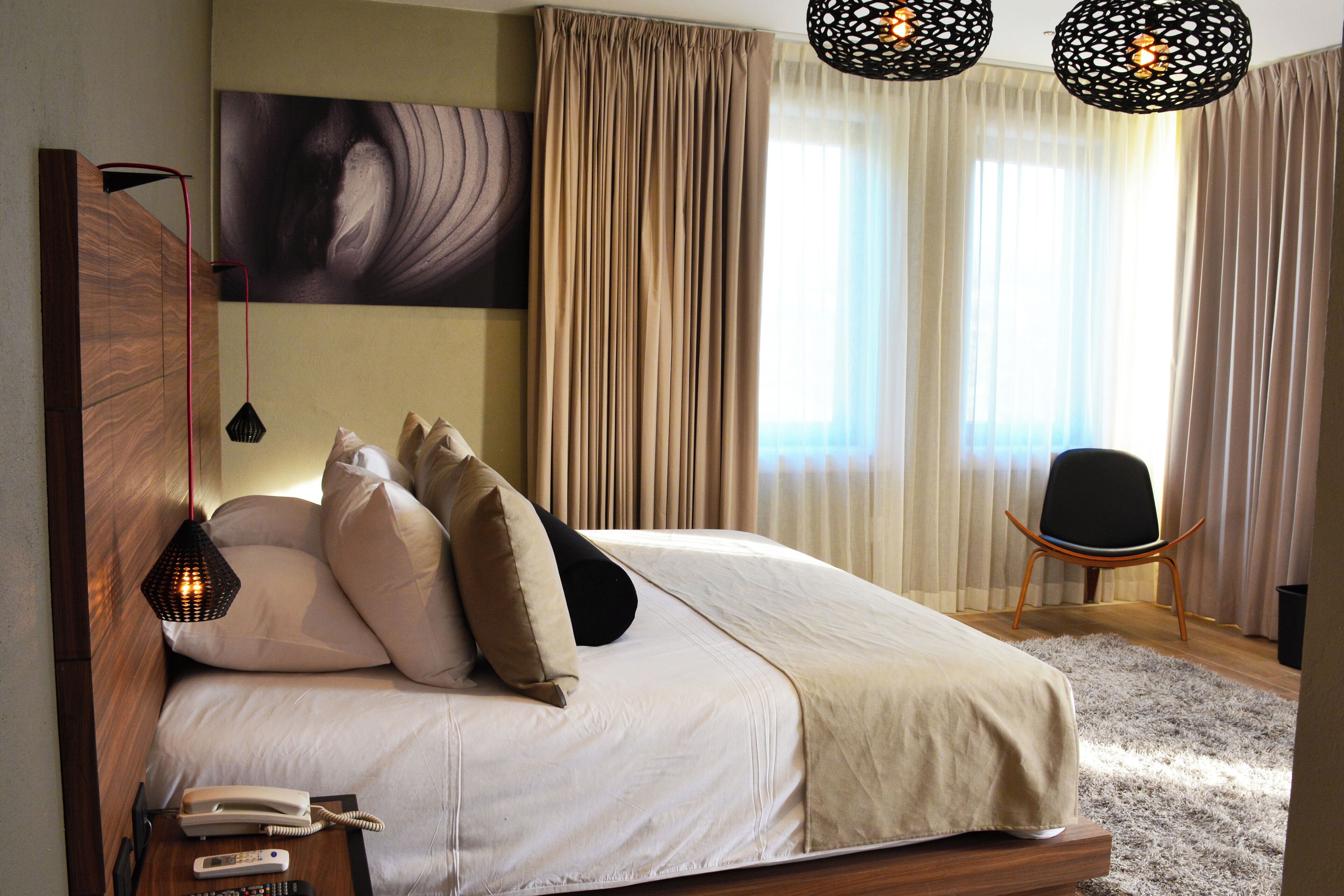 Quarto com cama grande, telefone de apoio, cadeira e um quadro na parede.