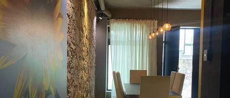 A modern dining area with a stone accent wall, a large floral mural, and a dining table with chairs.
