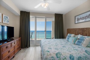 Relax in this serene retreat with a large bed, flat-screen TV, and sliding glass door leading to a balcony with ocean views.