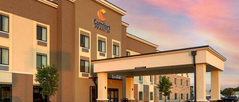 A Comfort Inn & Suites building with a brick facade, multiple windows, and a covered entrance area.