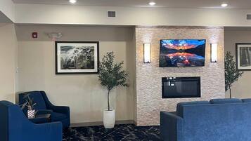 A lobby with a seating area, a mounted TV, and a framed picture on the wall.