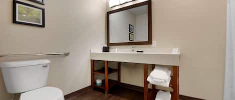 A bathroom with a toilet, a sink with a mirror above it, and shelves with towels.