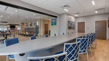 A conference room with a long table, blue chairs, and a glass partition.