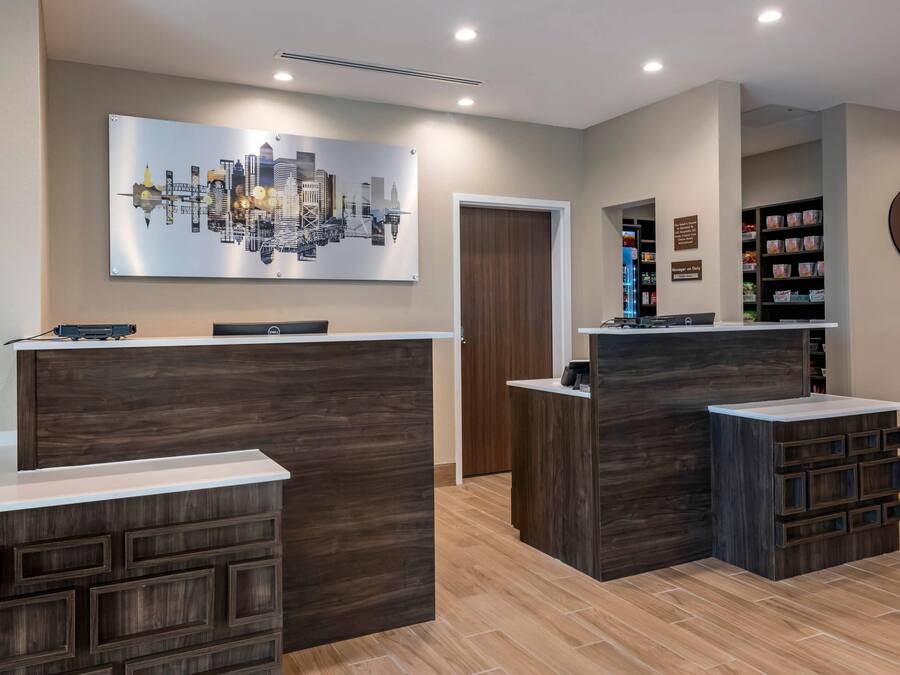 A reception area with wooden reception desks, a cityscape artwork, and a coffee machine.