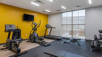Et fitnessrum med løbebånd, cardioudstyr og håndvægte.
